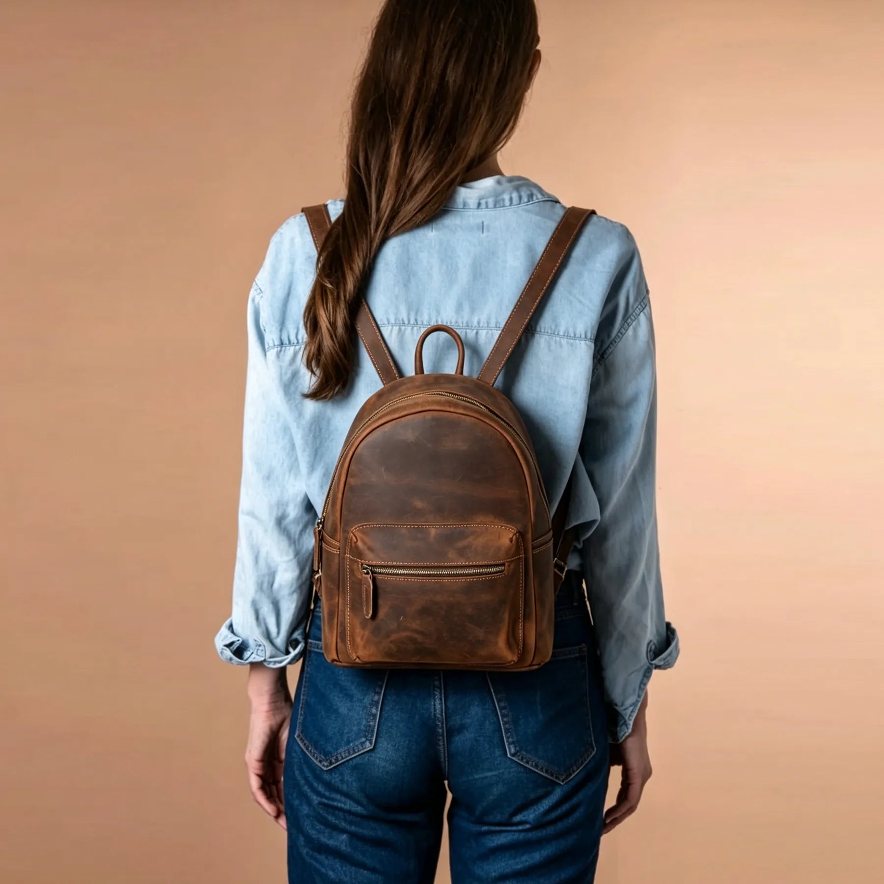 Person wearing a brown leather backpack against a beige background