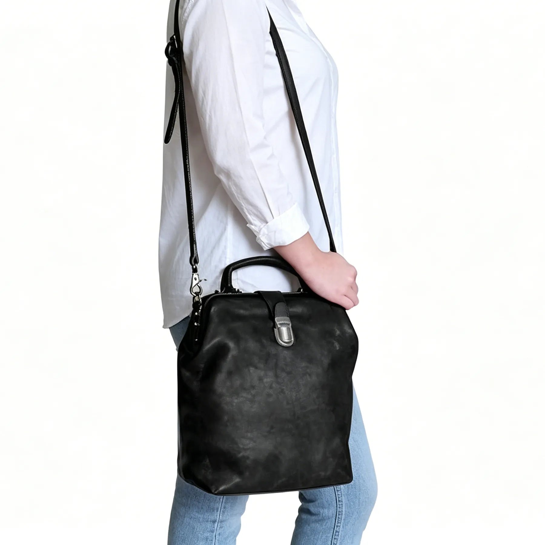 Person holding a black leather handbag against a white background