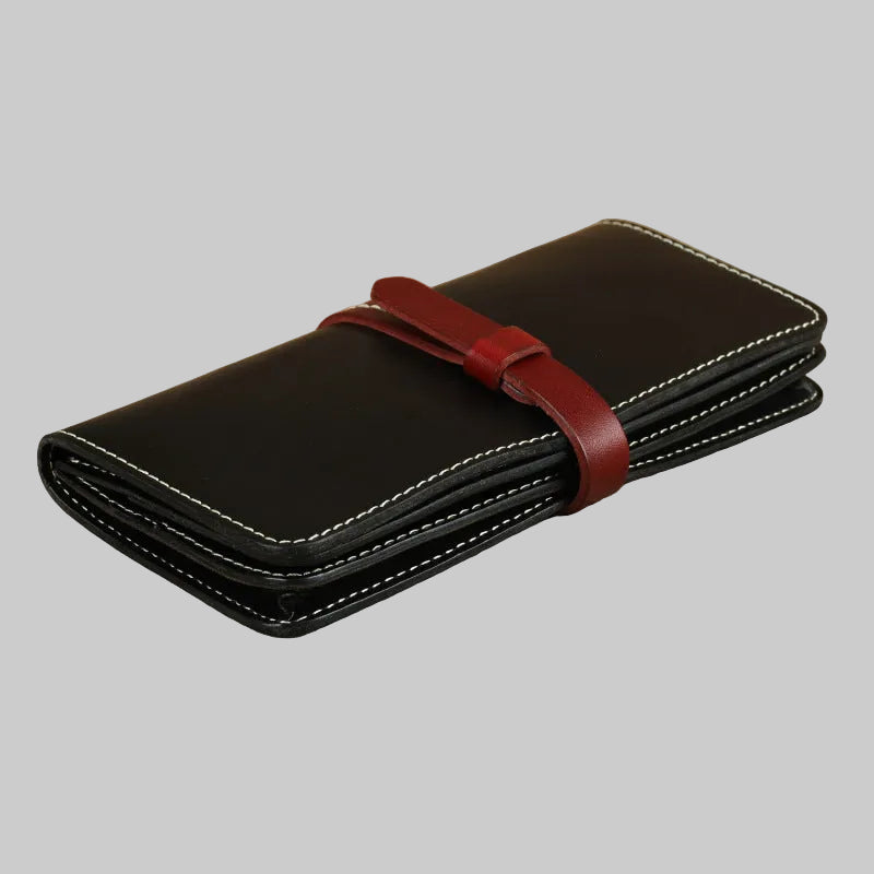 Black leather wallet with a red strap on a beige surface