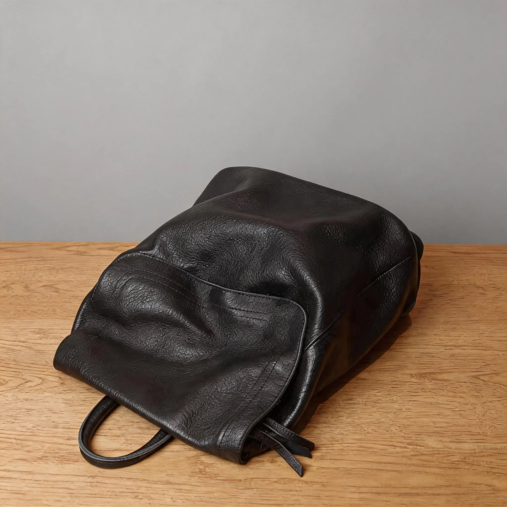 Black leather bag on a wooden surface with a gray background