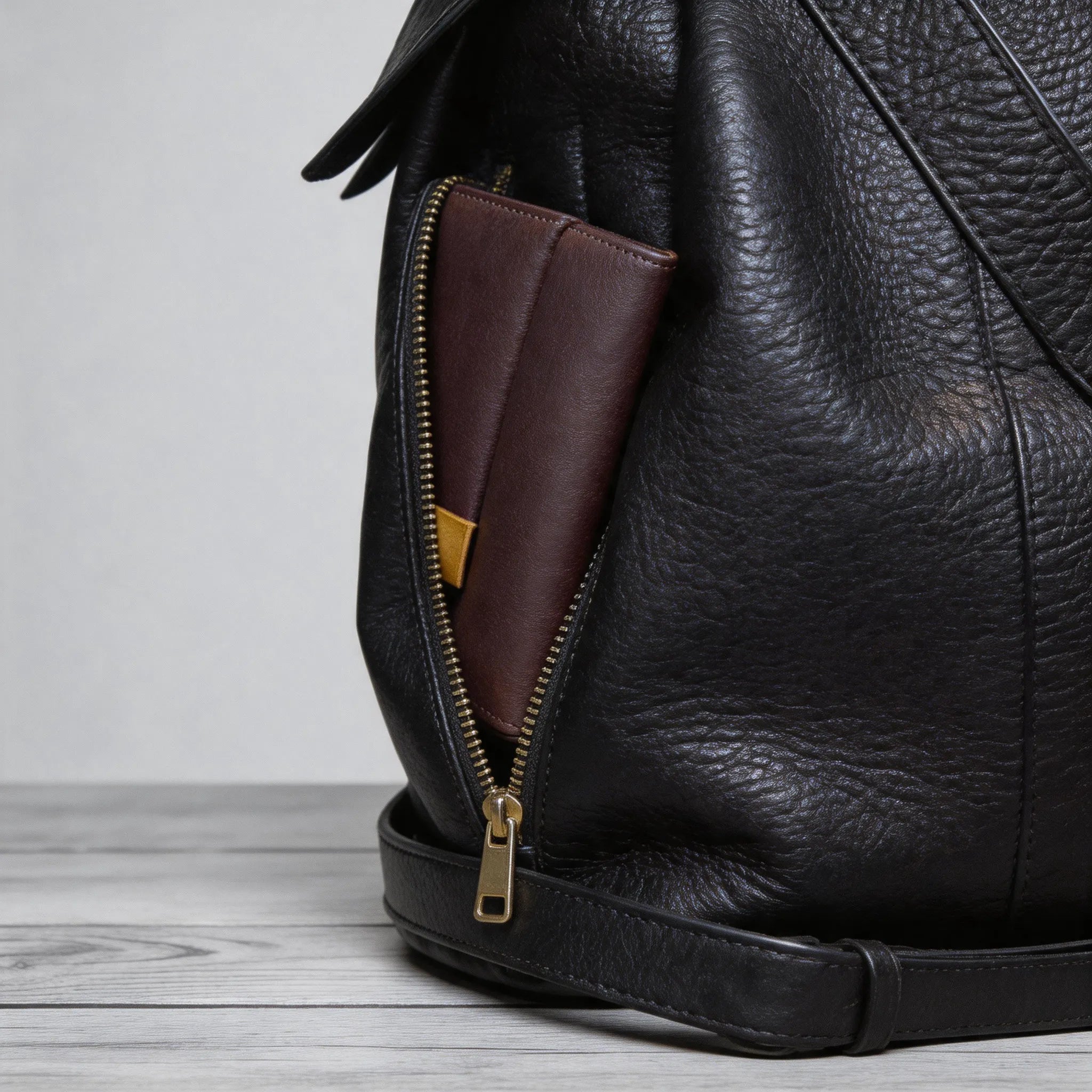 Black leather bag with a brown wallet inside on a wooden surface
