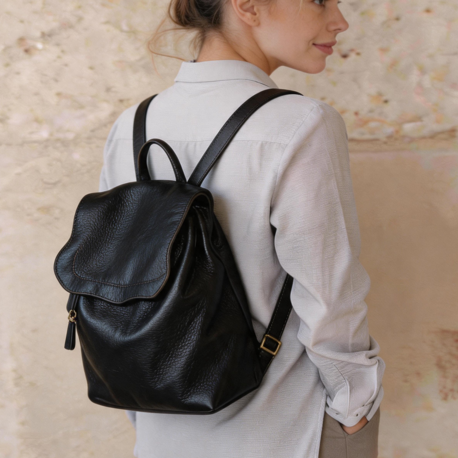 Woman wearing a black backpack against a textured beige wall