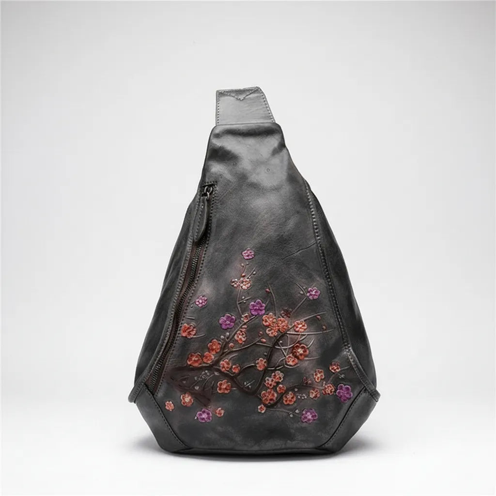 Black sling bag with floral embroidery on a light gray background