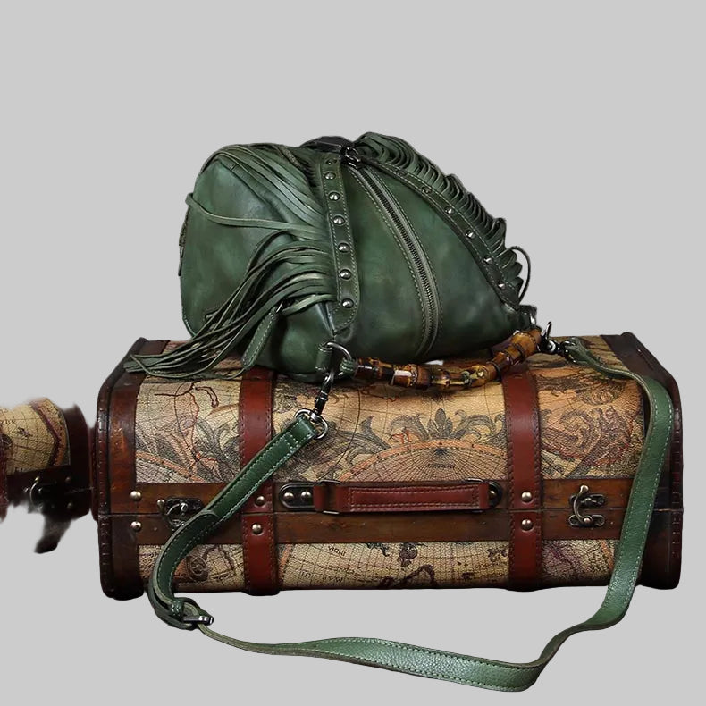 Green leather bag with studded details on top of a vintage-style suitcase with world map design.