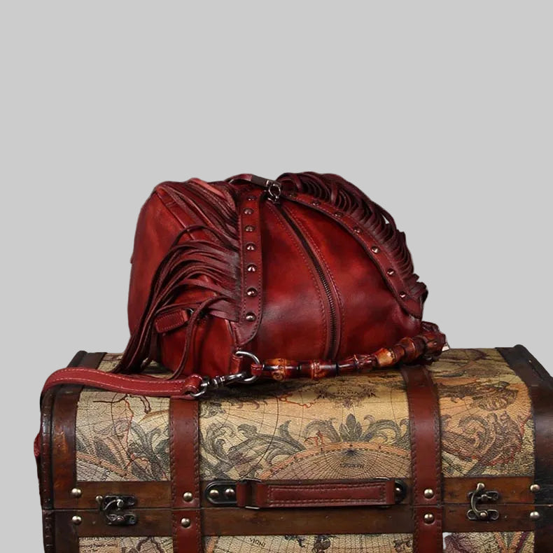 Red leather bag on top of a vintage-style suitcase with world map design