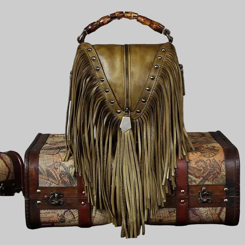 Brown leather handbag with fringe and studs on a gray background