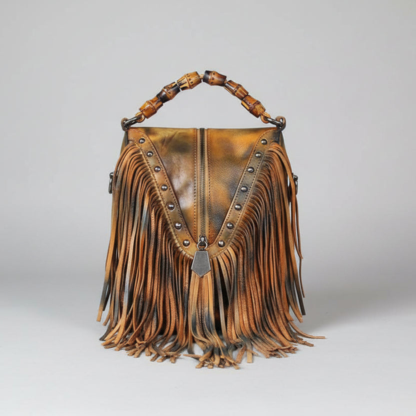 Brown leather handbag with fringe and studded details on a light gray background