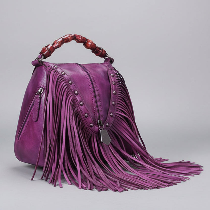 Purple handbag with fringe details on a gray background