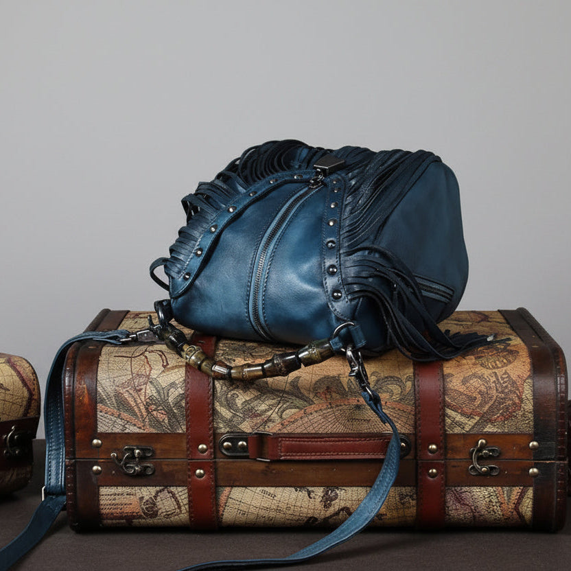 Blue leather handbag with fringe details on a world map suitcase