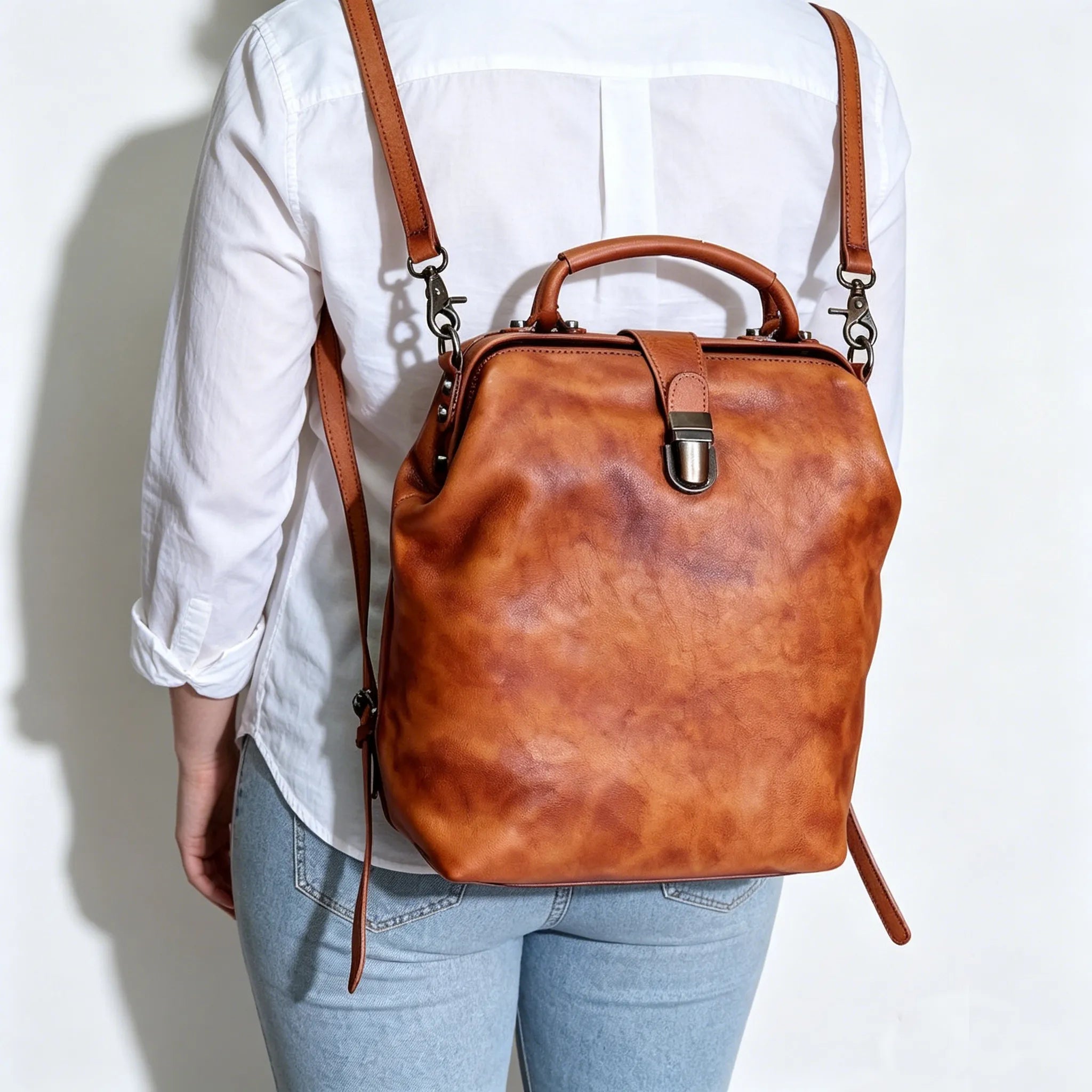 Brown leather backpack worn by a person on a white background