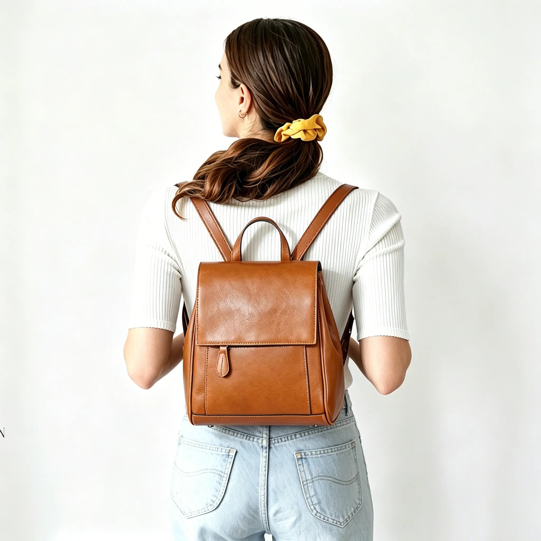 Person wearing a brown leather backpack on a white background
