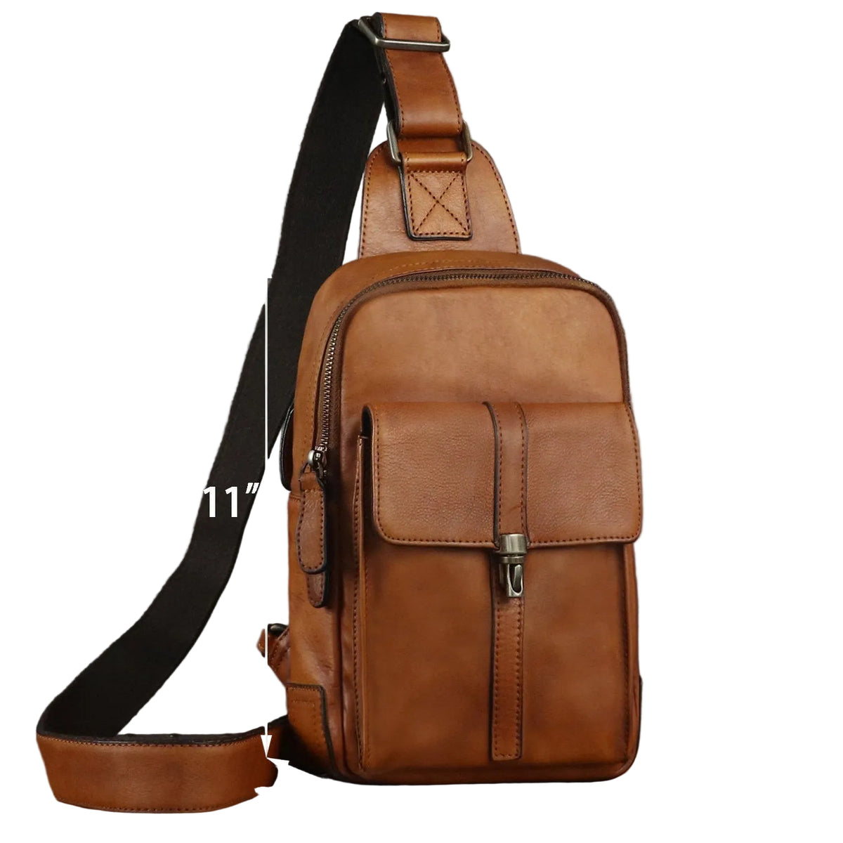 A brown leather sling bag with a black shoulder strap, shown with dimension arrows and labels indicating 11 inches height, 7.3 inches width, and 3.