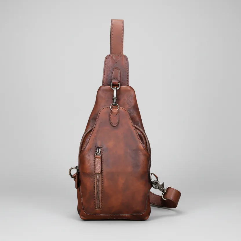 Brown leather sling bag on a light gray background