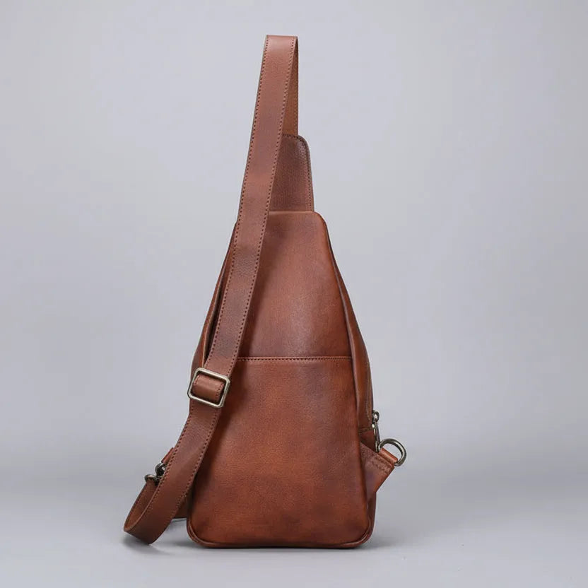 Brown leather sling bag on a light gray background