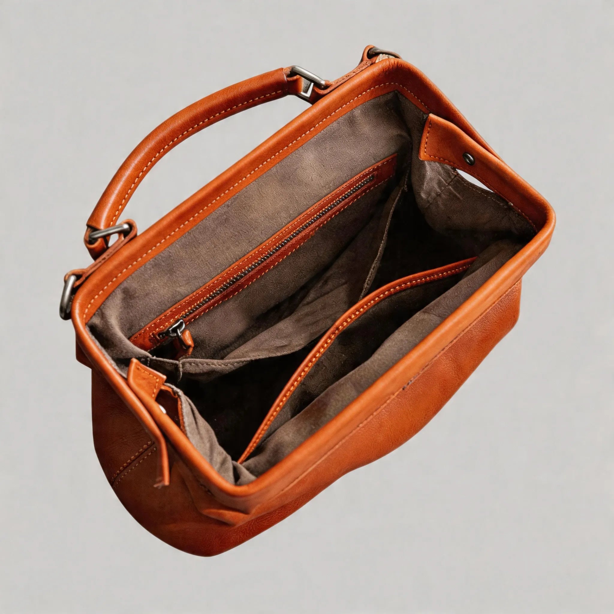 Brown leather handbag with open front pocket on a gray background
