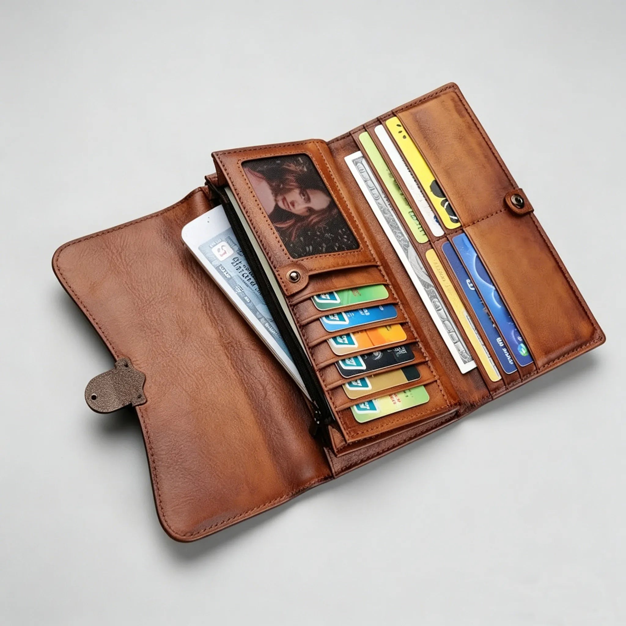 Brown leather wallet with various cards and a photo inside on a light gray background