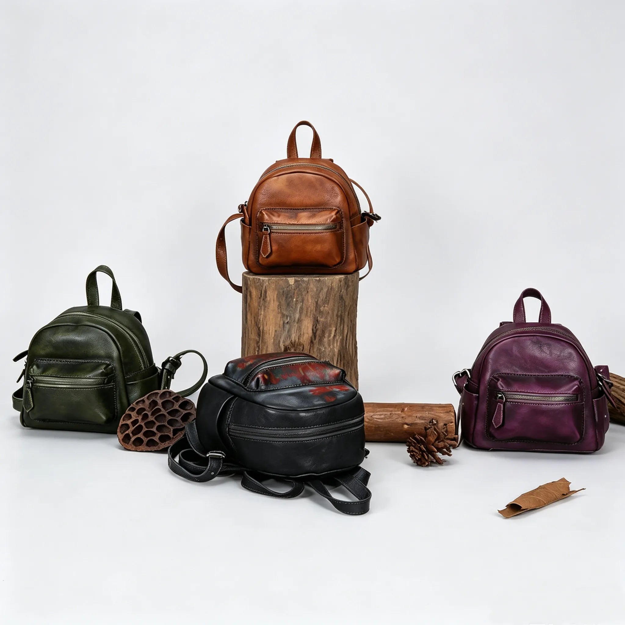 Four leather backpacks in different colors on a white background