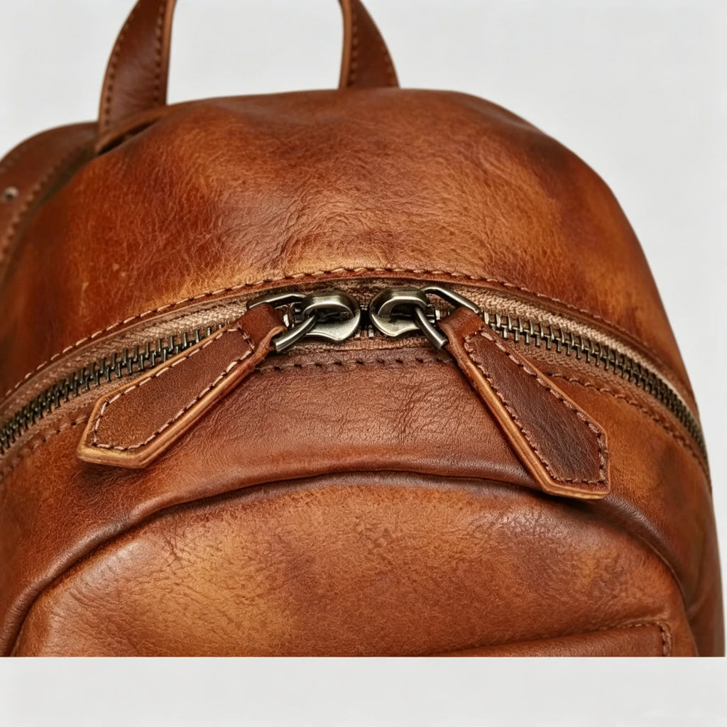 Brown leather backpack with a zipper on a light gray background