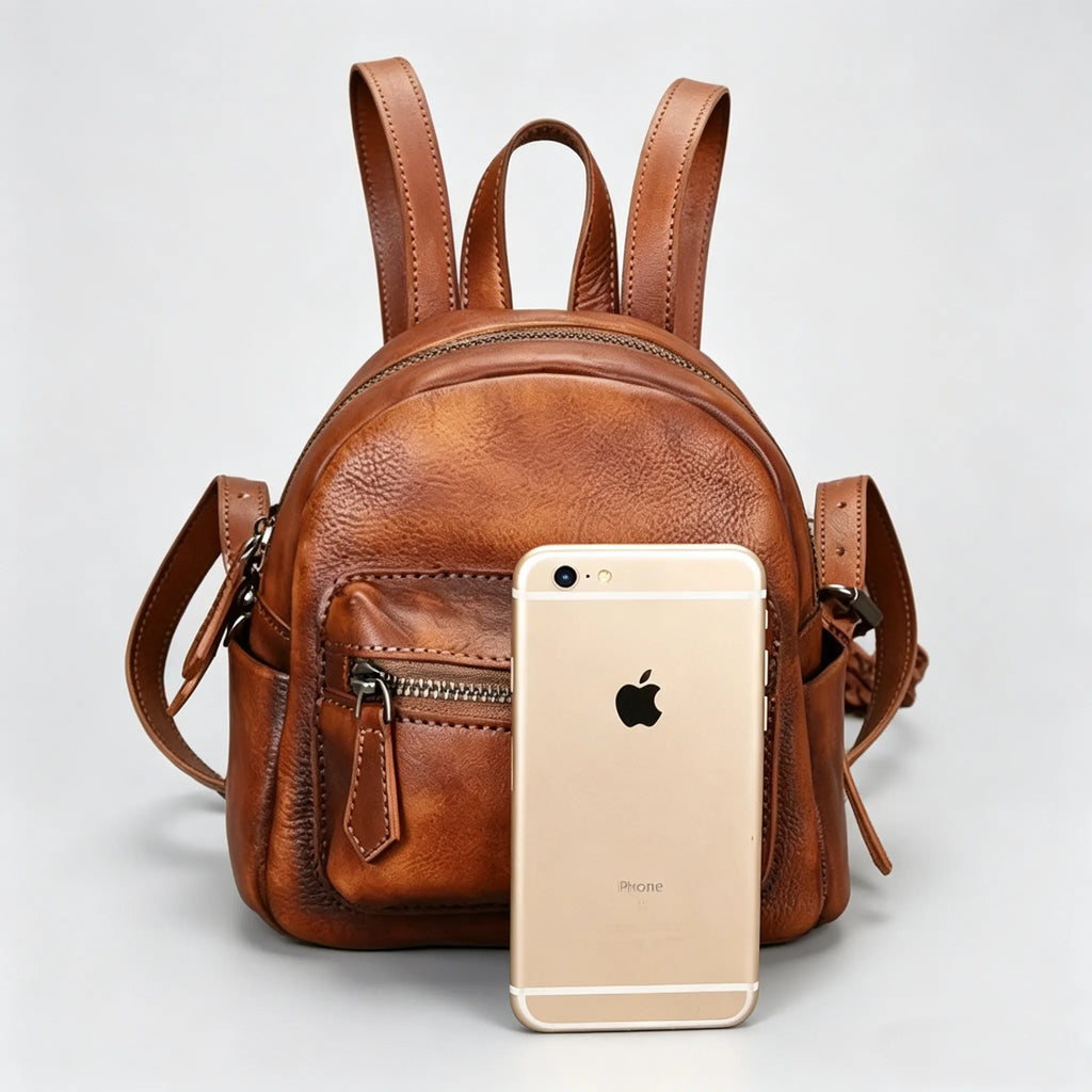 Brown leather backpack with an iPhone 6s Plus on a light gray background