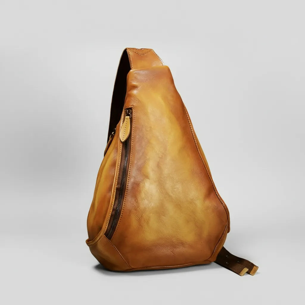 Brown leather sling bag on a light gray background