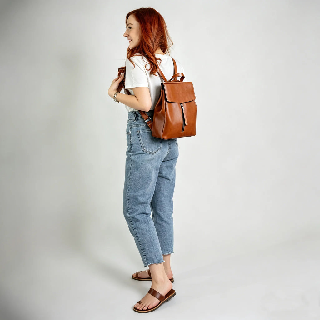 Woman carrying a brown leather backpack on a plain background
