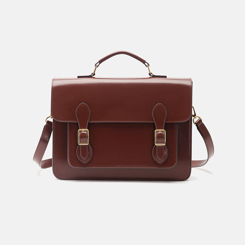 Brown leather satchel bag with gold buckles on a light gray background