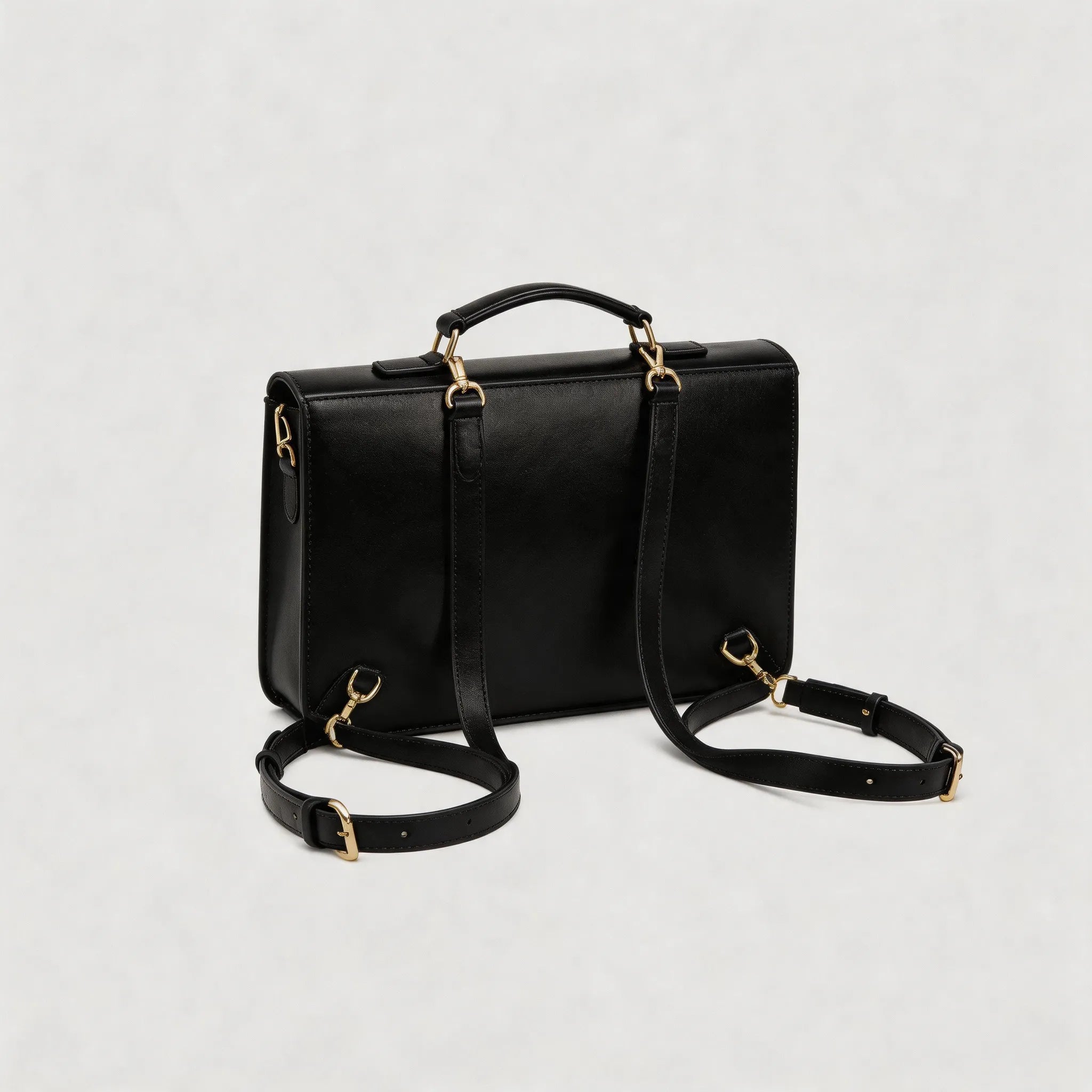 Black leather handbag with gold hardware on a light gray background