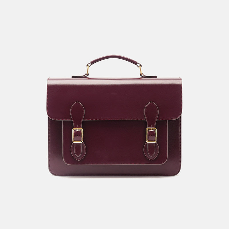 Burgundy leather satchel with gold buckles on a light gray background