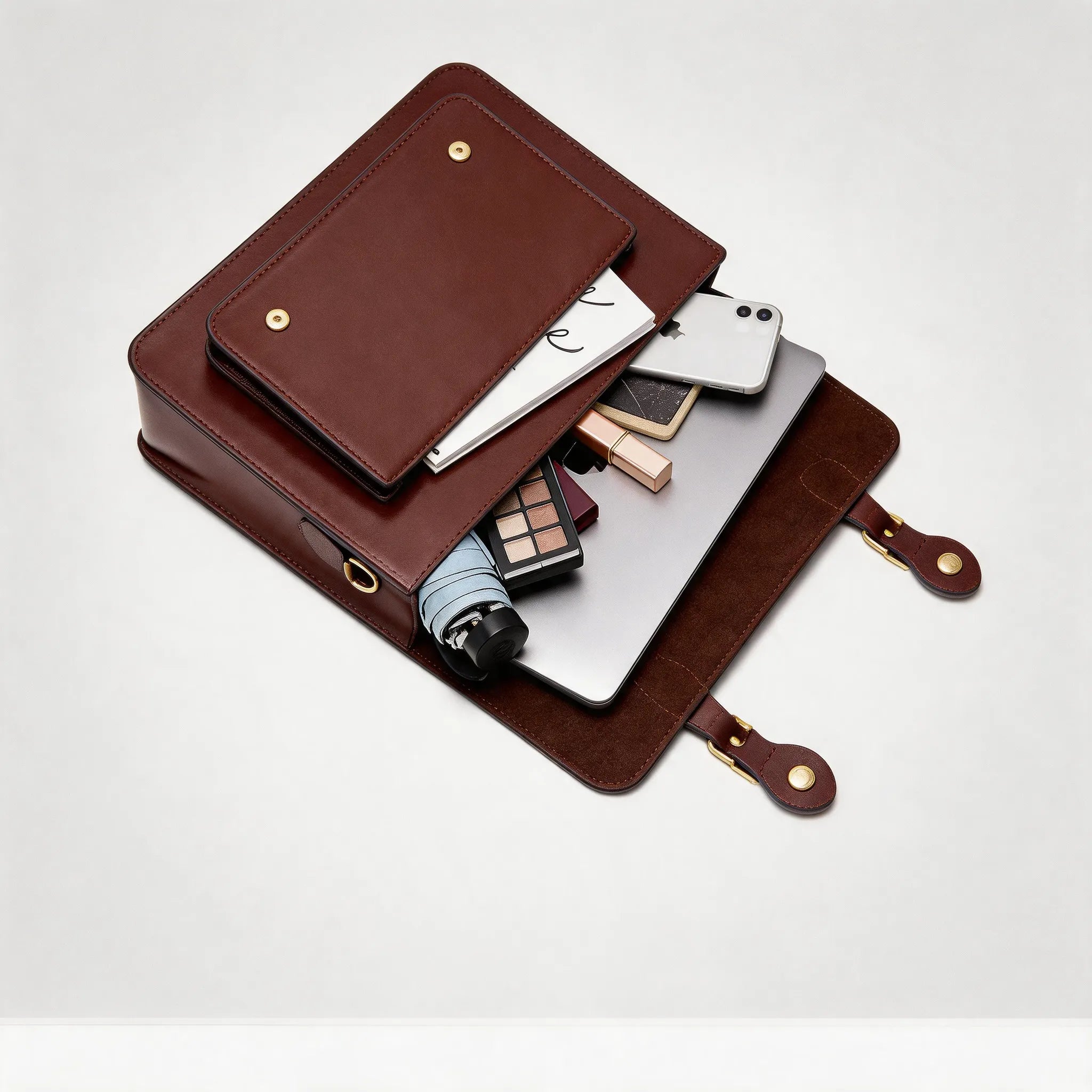 Brown leather travel organizer with various items on a white background