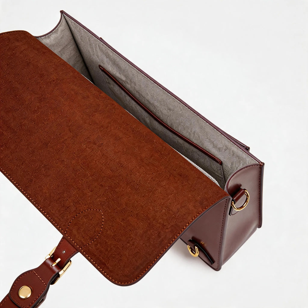 Brown leather handbag with gold hardware on a light gray background