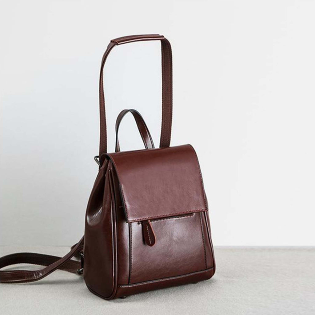 Brown leather backpack on a light gray surface with a white background