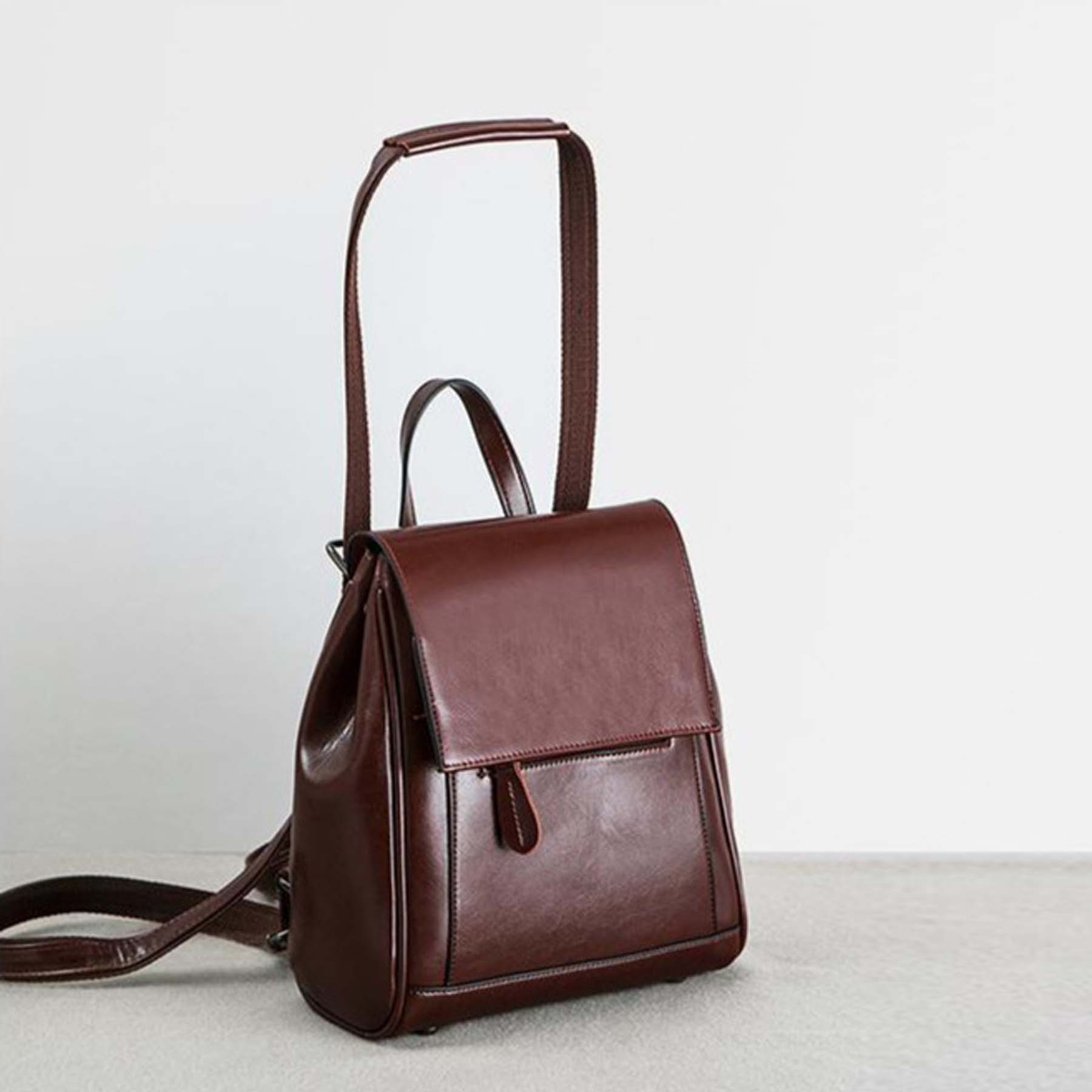 Brown leather backpack on a light gray surface with a white background