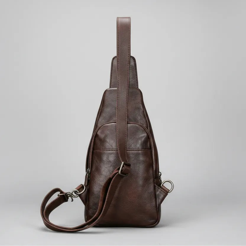 Brown leather sling bag on a light gray background