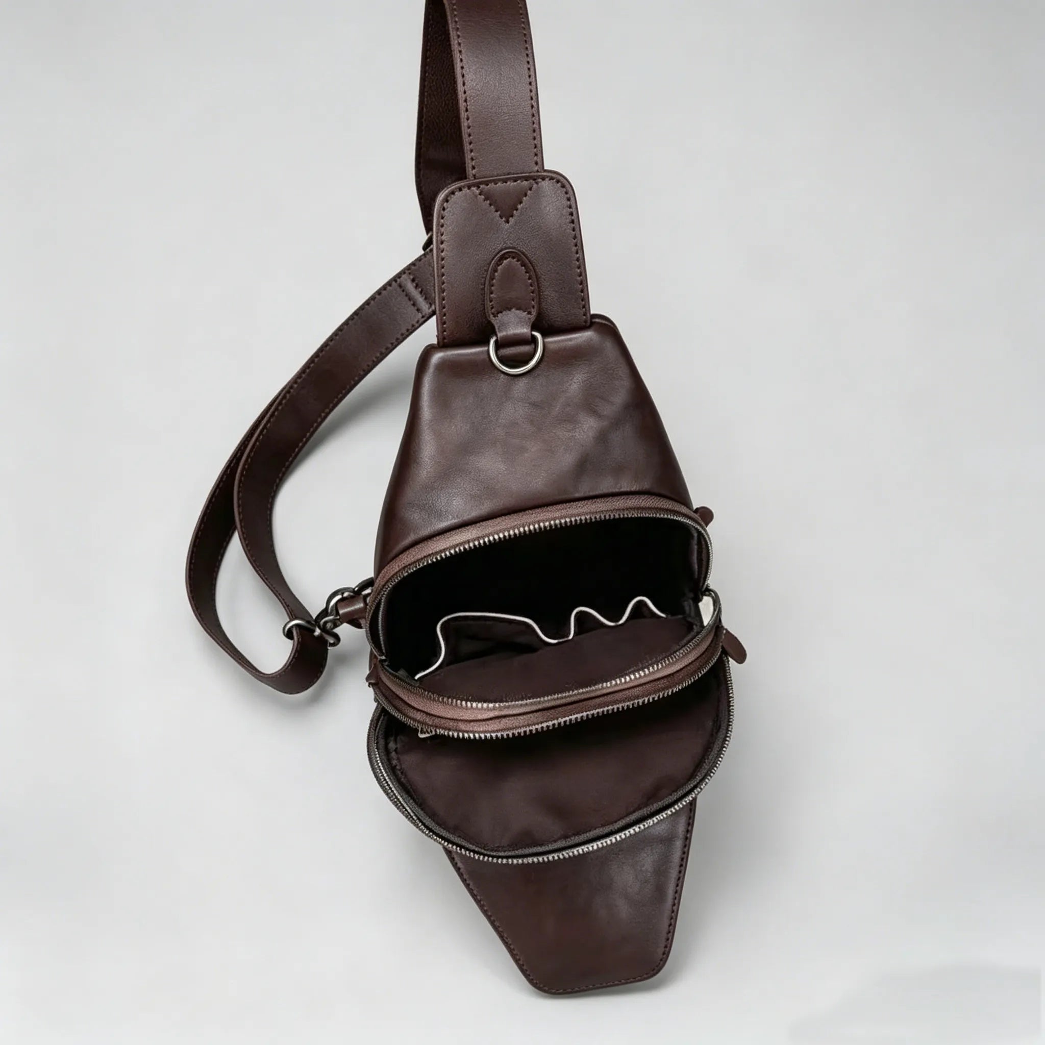 Brown leather sling bag on a light gray background