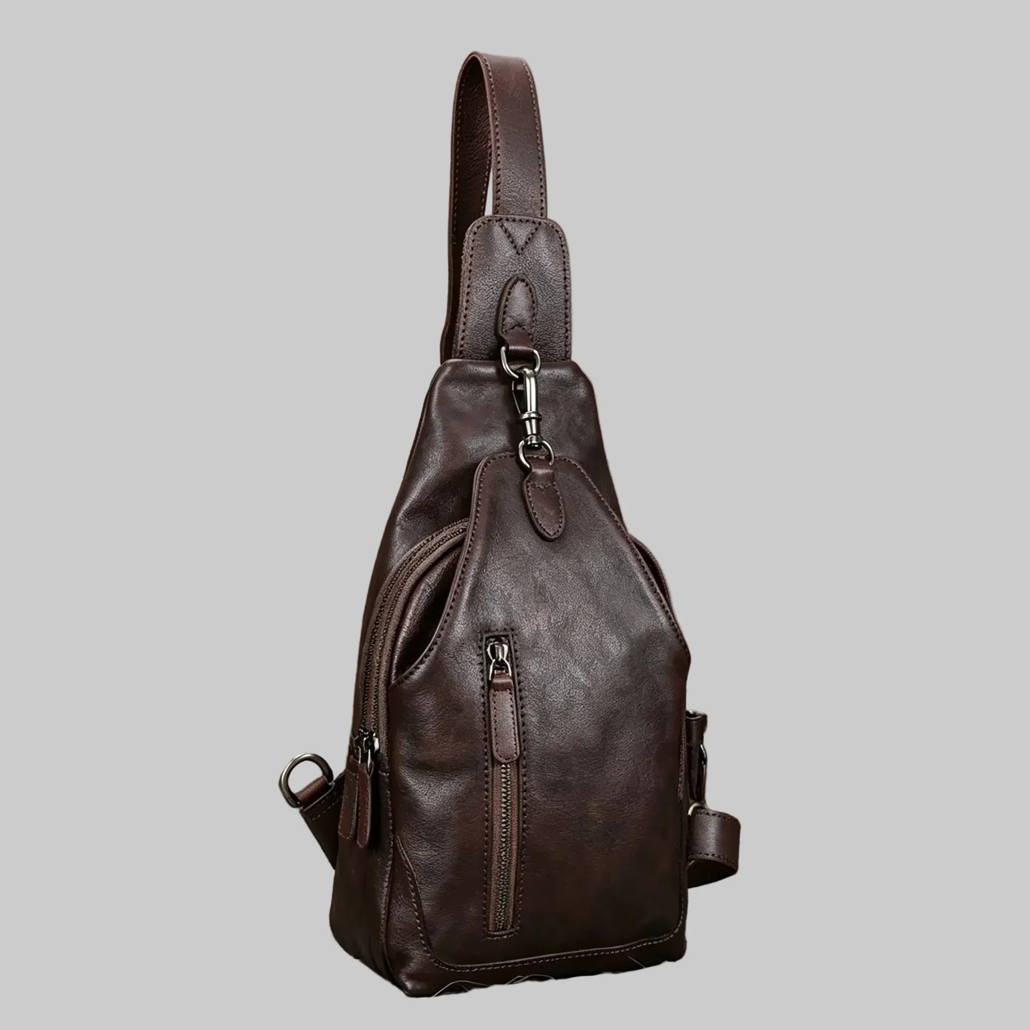 Brown leather sling bag on a light gray background
