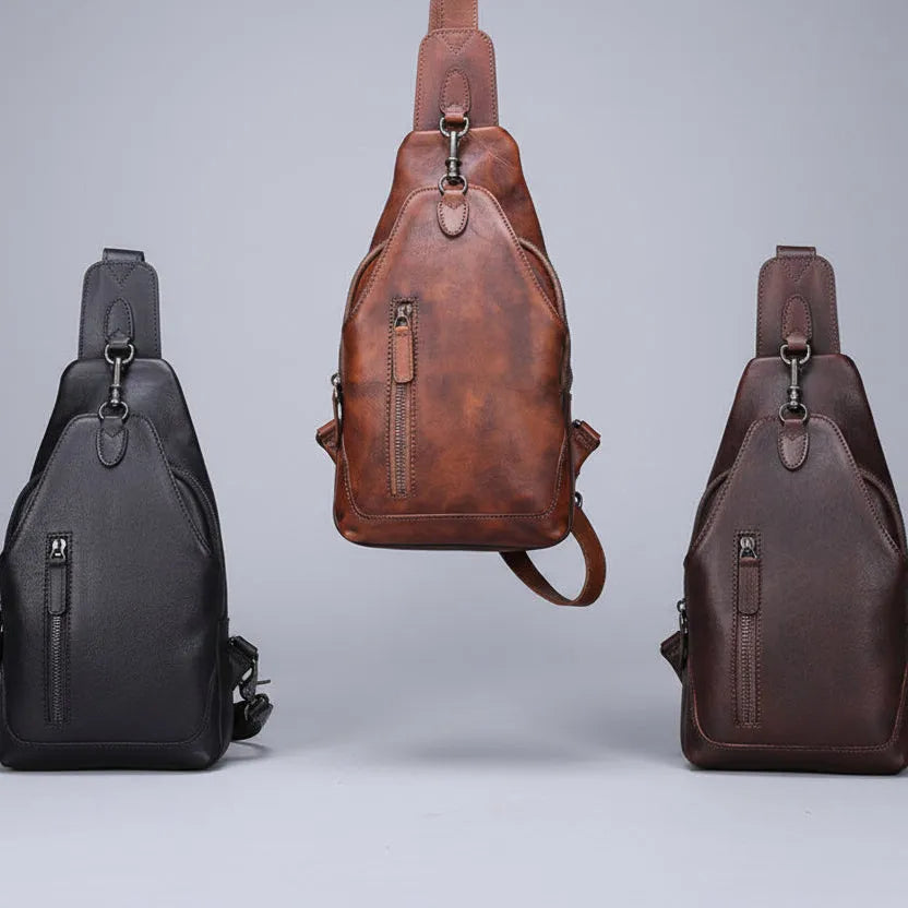 Three leather sling bags in black, brown, and another brown shade on a light gray background.