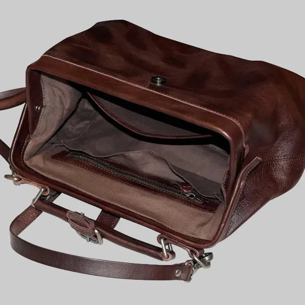 Brown leather handbag with open top on a light gray background