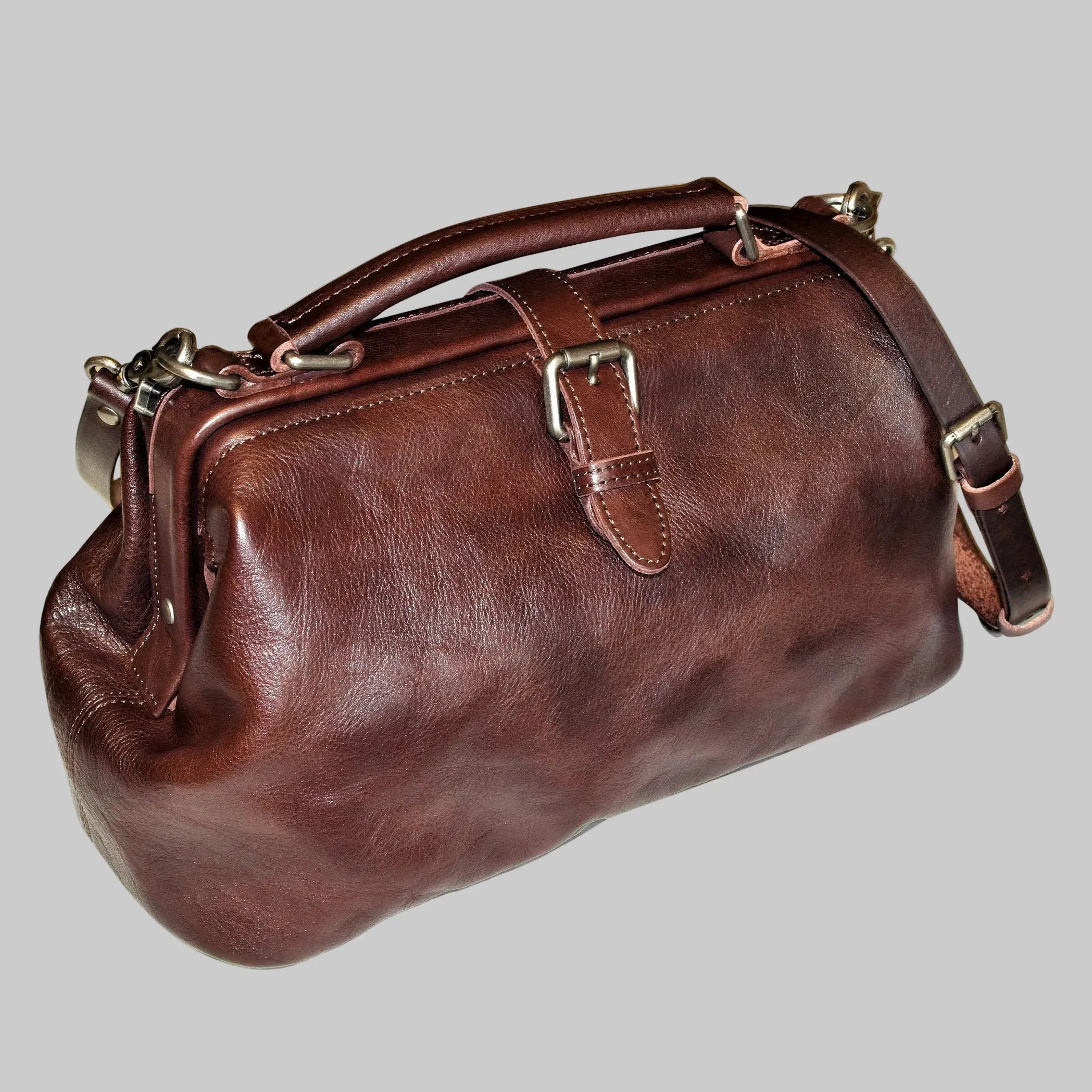 Brown leather handbag with a strap on a white background