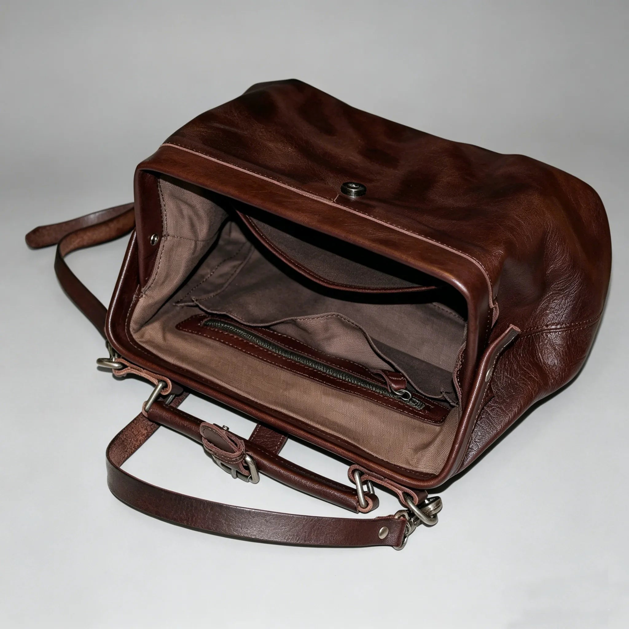 Brown leather bag with open front pocket on a light gray background
