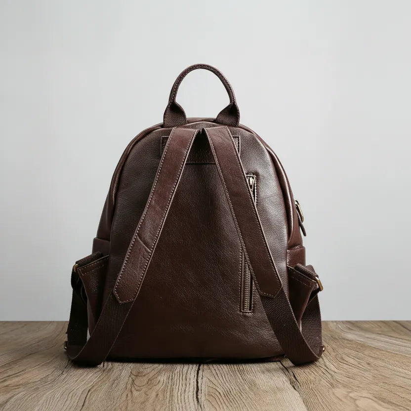 Brown leather backpack on a wooden surface with a light gray background