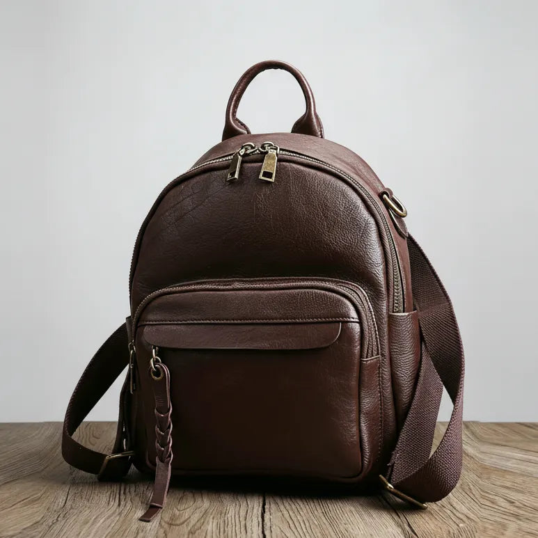 Brown leather backpack on a wooden surface with a light gray background