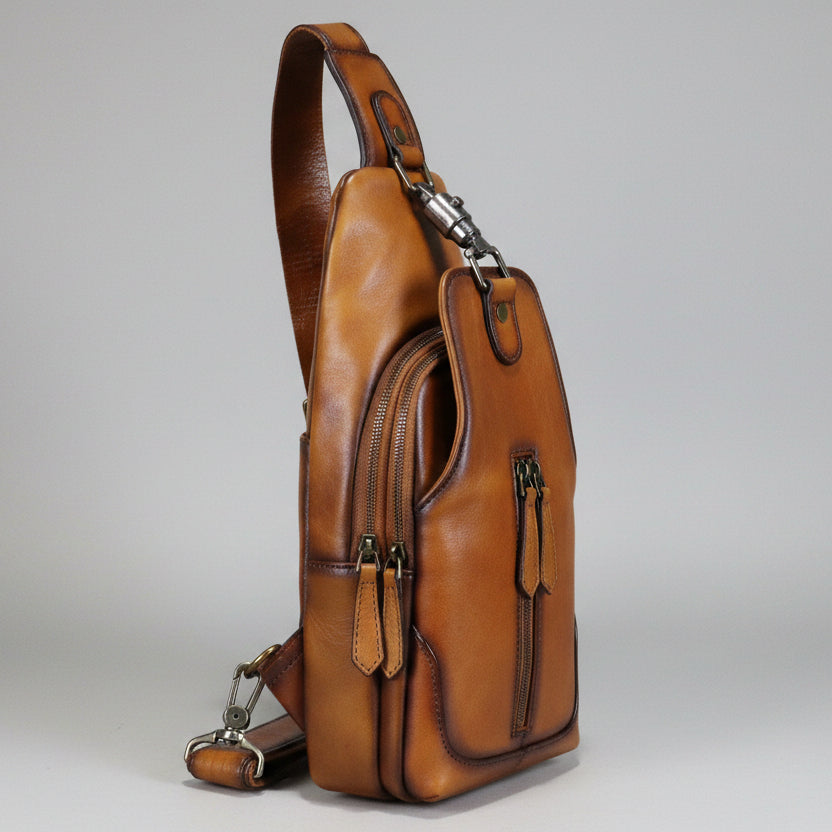 Brown leather sling bag on a light gray background