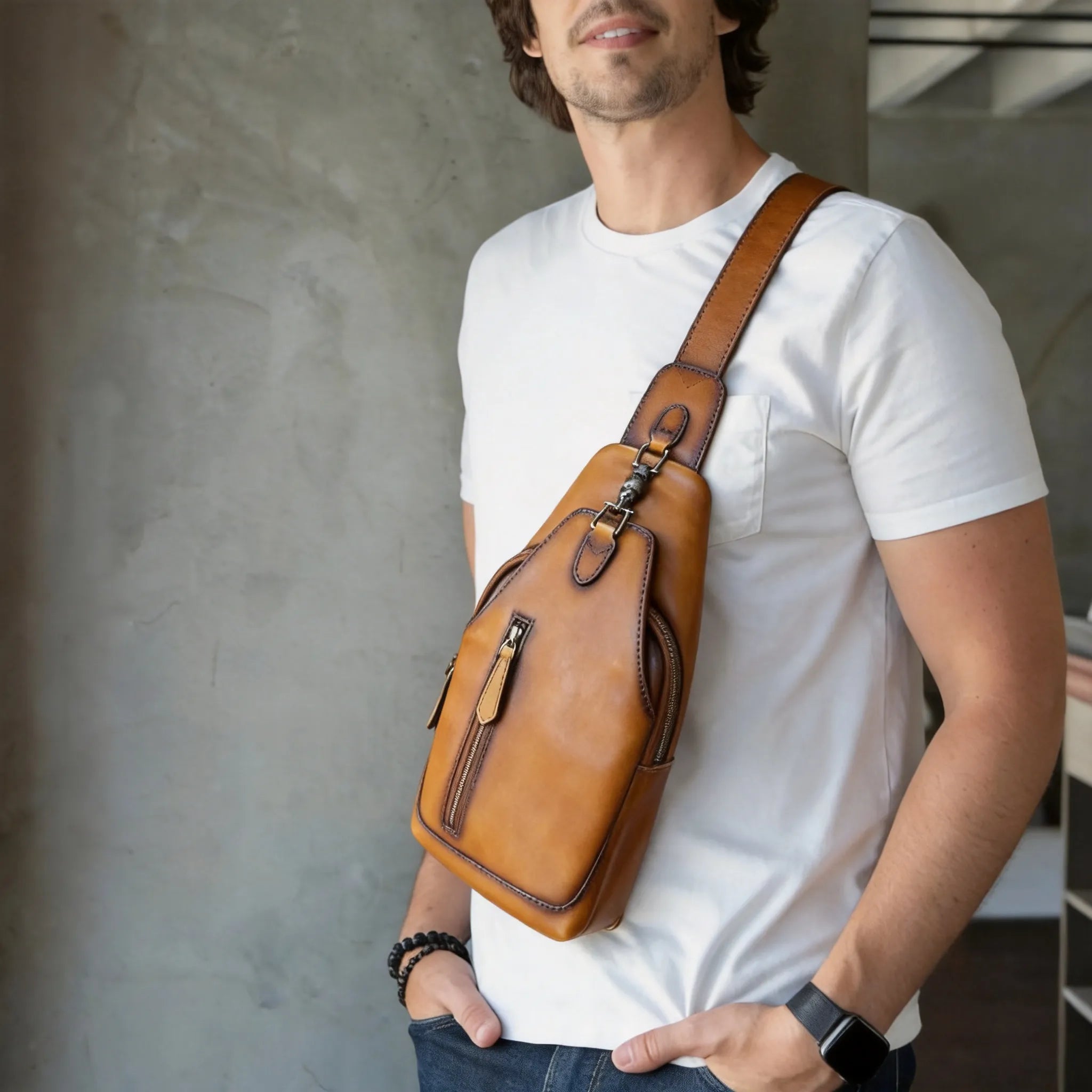 Man wearing a brown leather sling bag over his shoulder against a neutral background