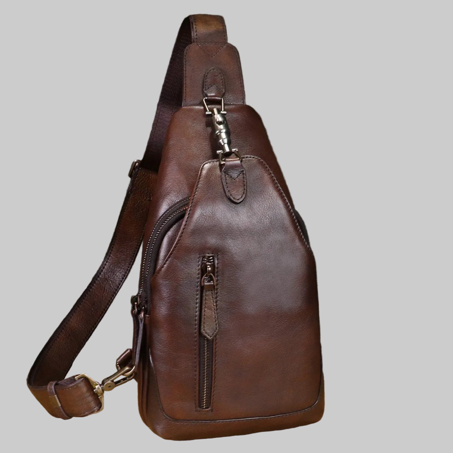 Brown leather sling bag on a light gray background