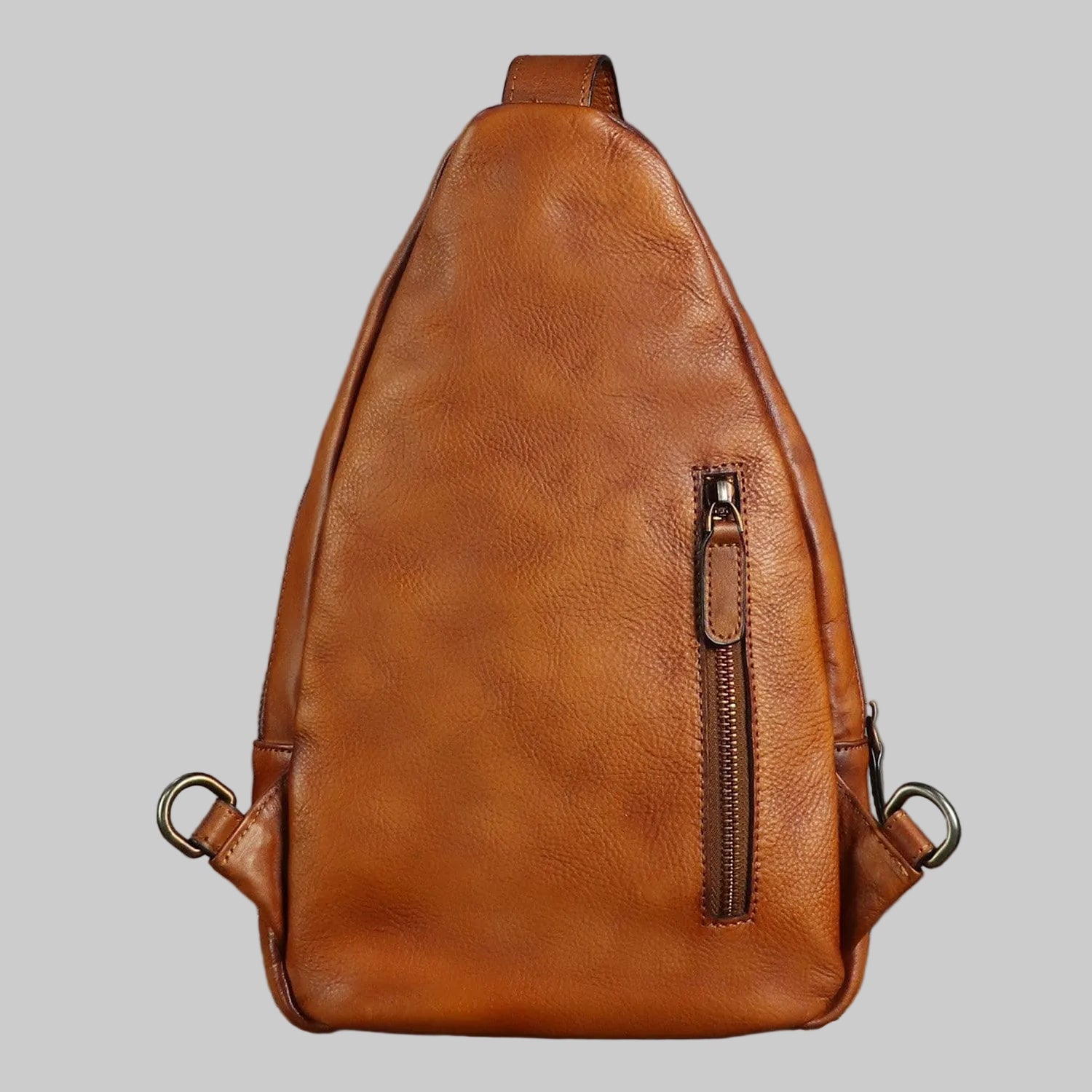 Brown leather sling bag on a gray background