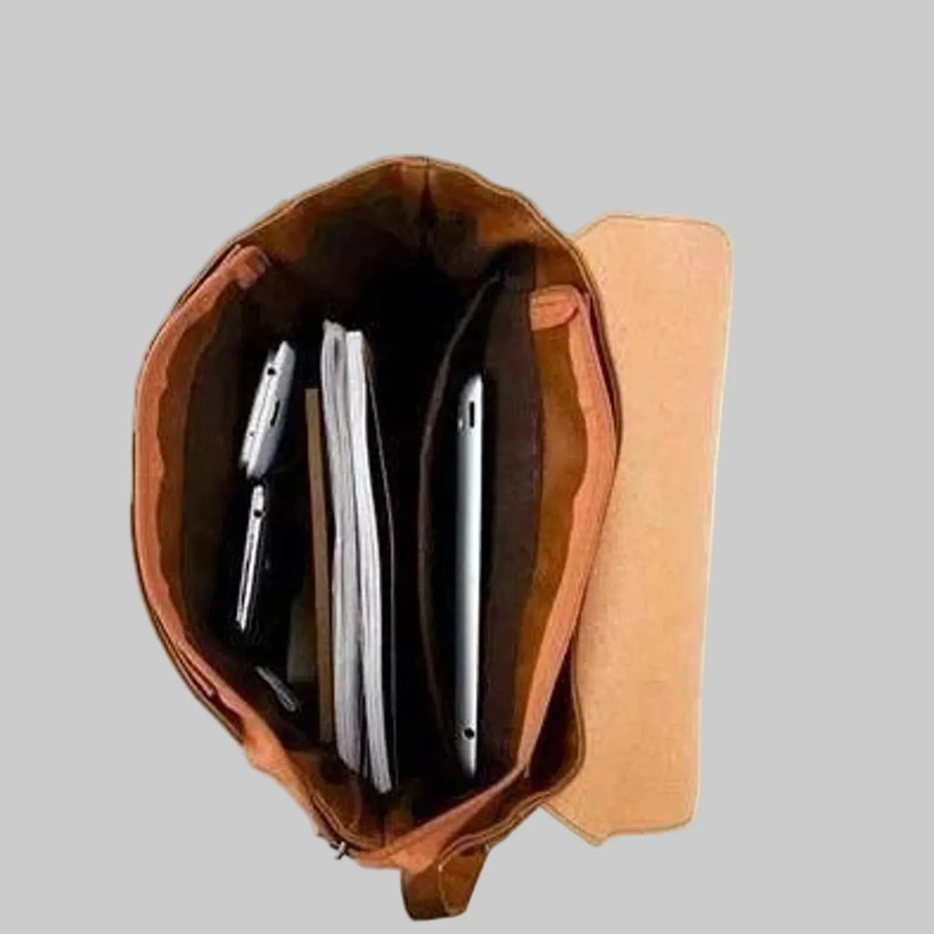 Brown leather pouch with a phone and pen on a gray background