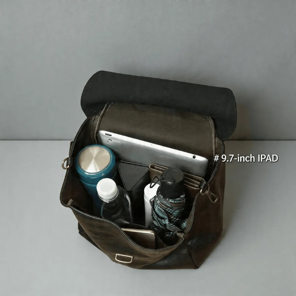 Brown leather bag with various items including a 9.7-inch iPad on a gray background