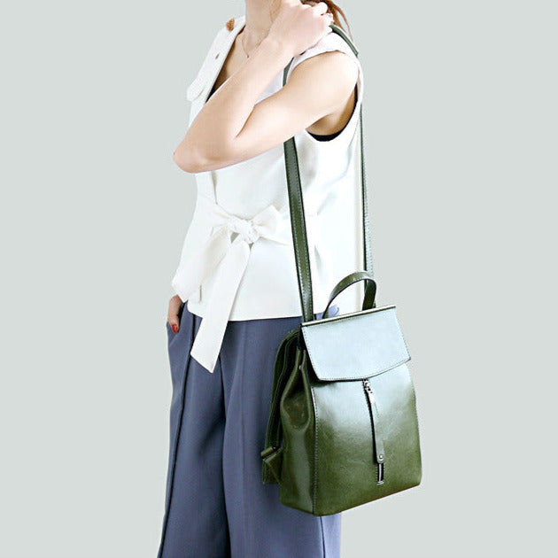 Person wearing a white sleeveless top and blue pants with a green backpack on a light gray background