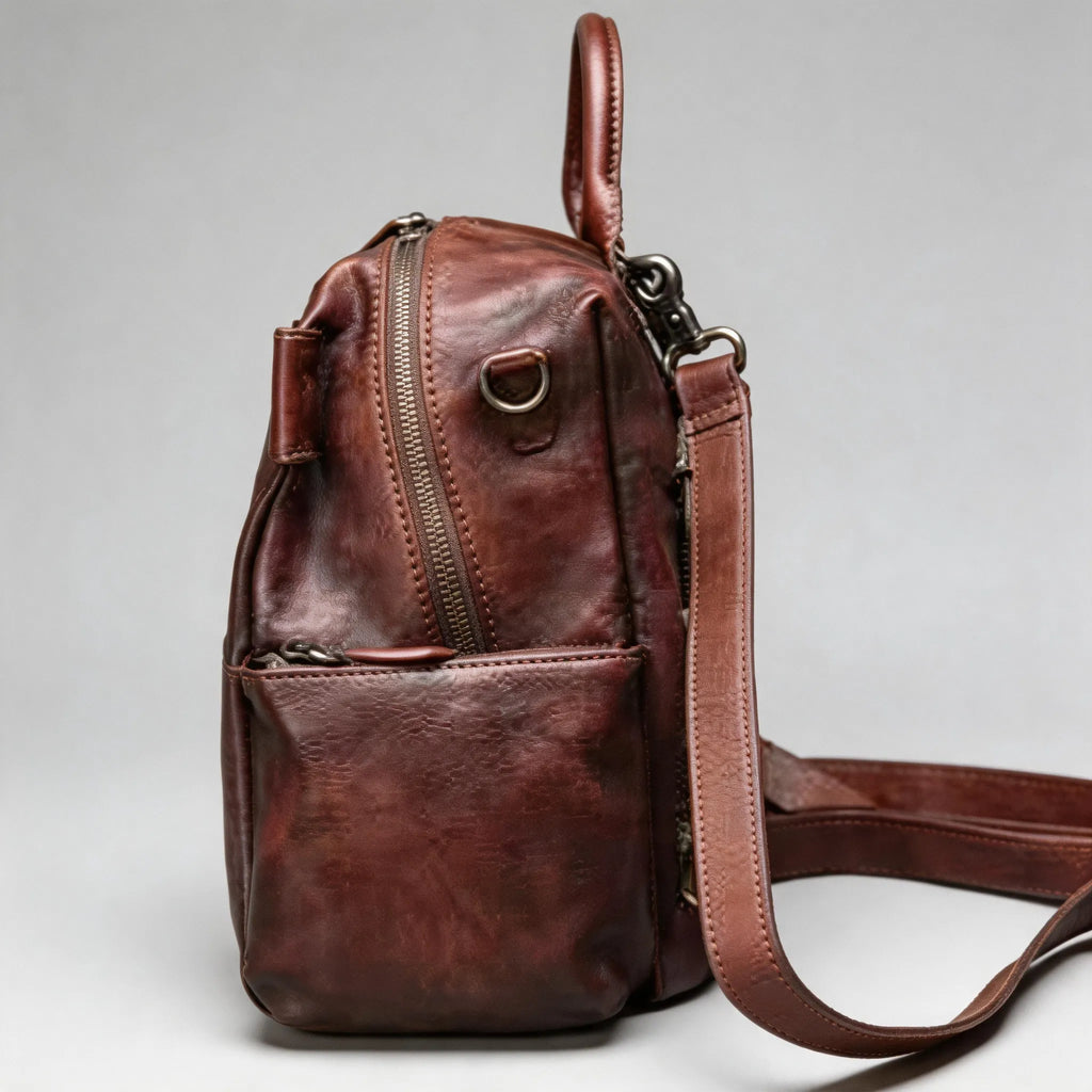 Brown leather backpack with a strap on a light gray background
