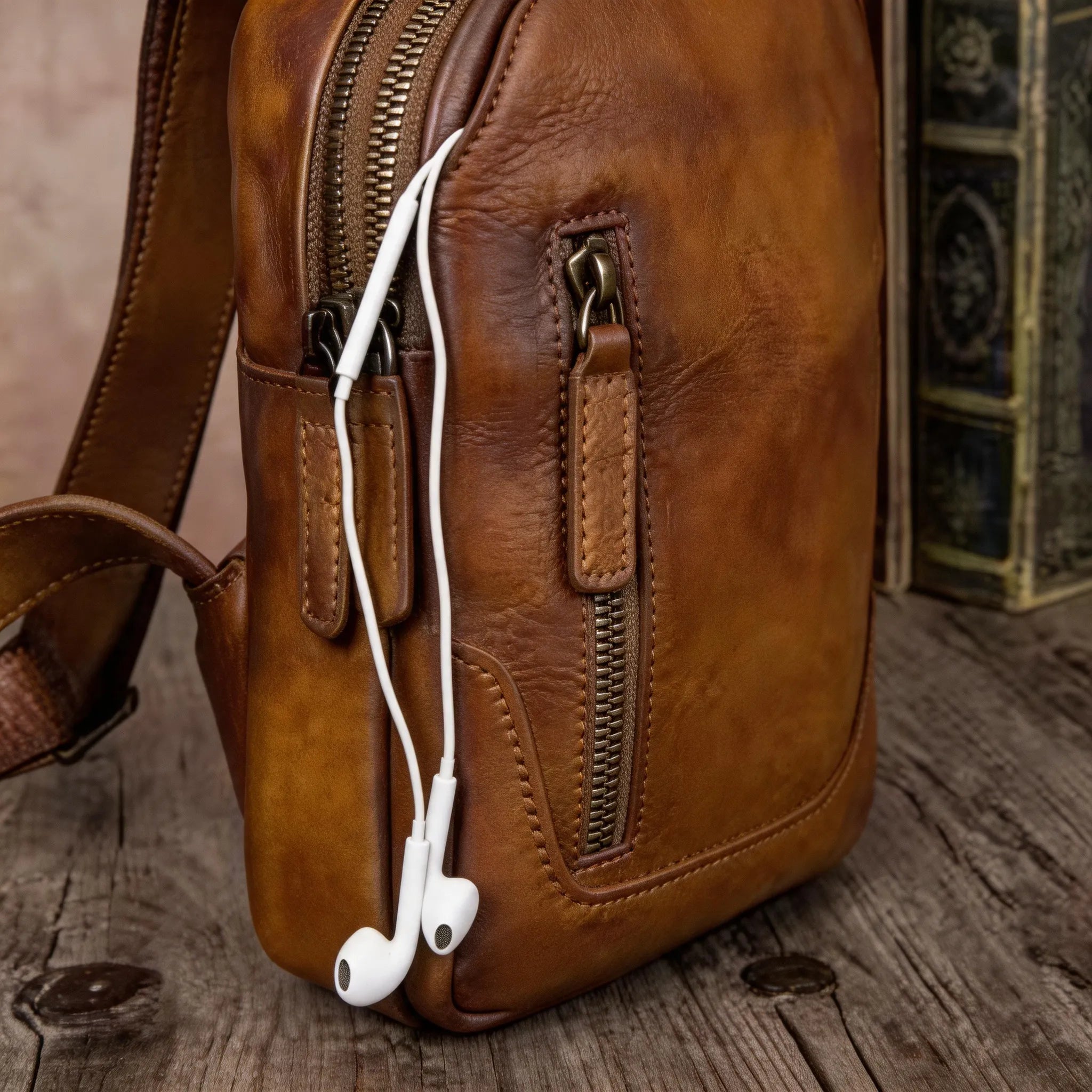 Brown leather bag with earphones on a wooden surface